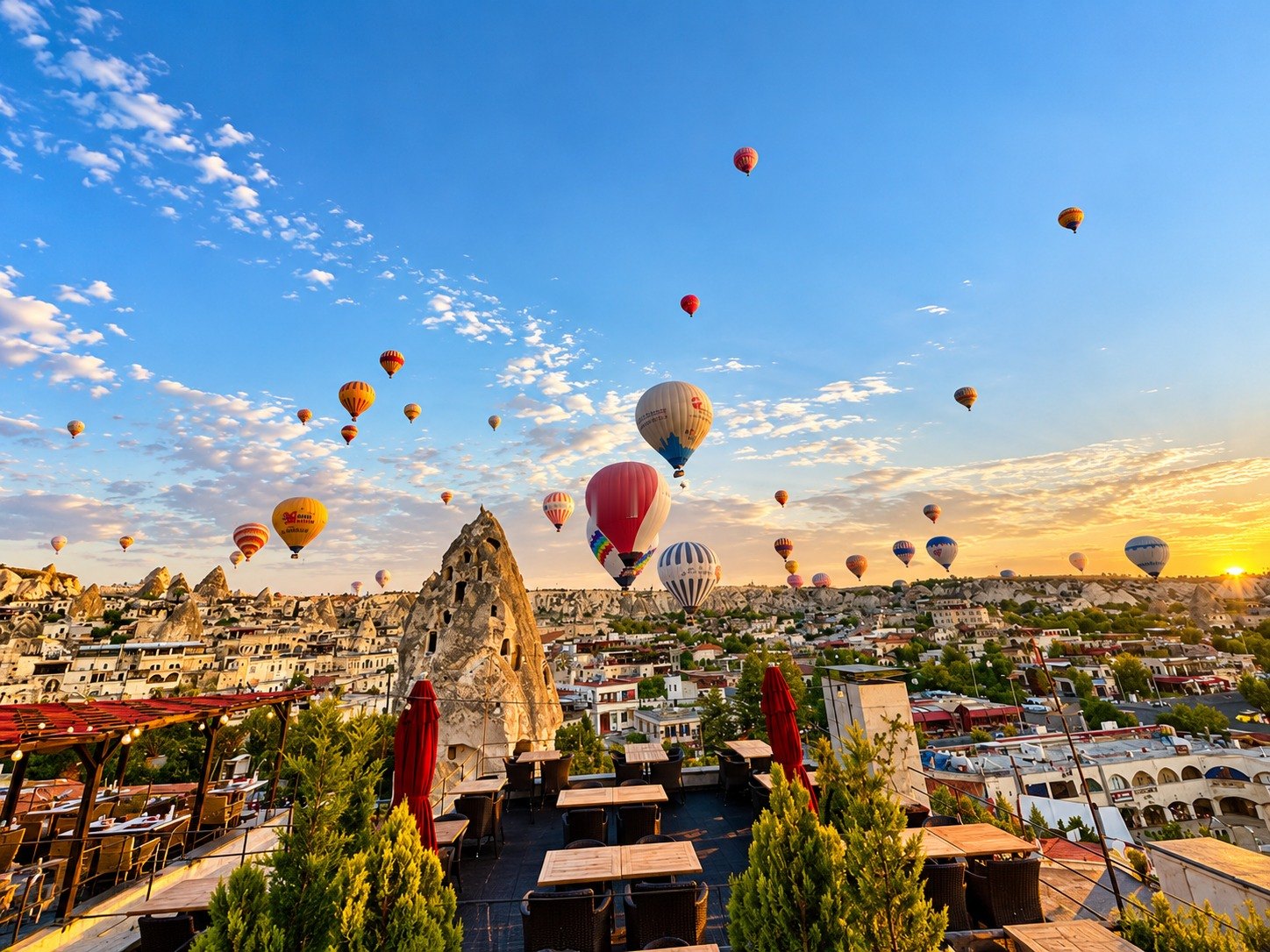 Rooftop terrace in Cappadocia at sunrise with balloons over the rock chimneys