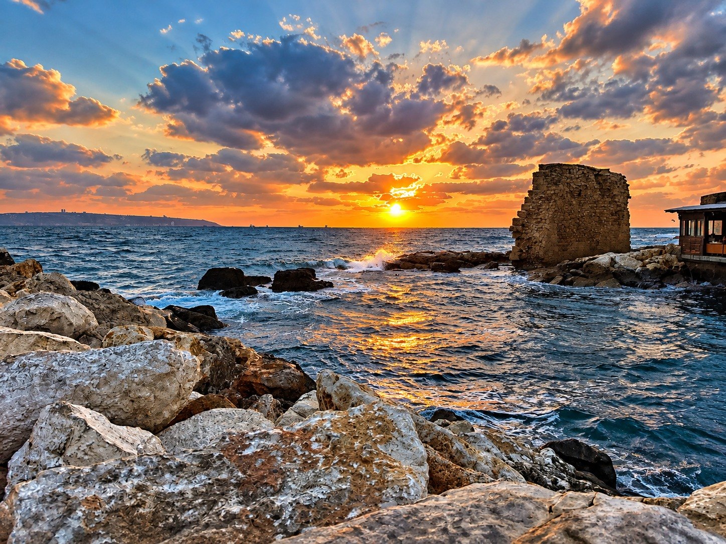 Sunset over the sea beside an ancient stone sea-wall ruin