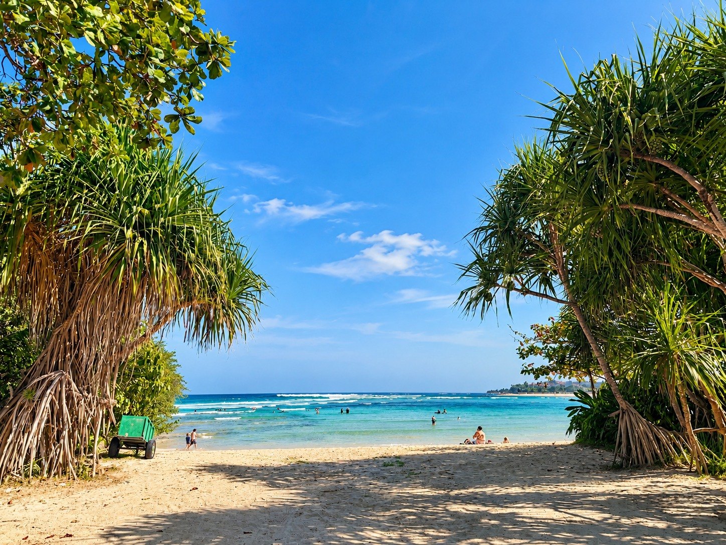 Sandy path between pandan trees to a turquoise Bali beach