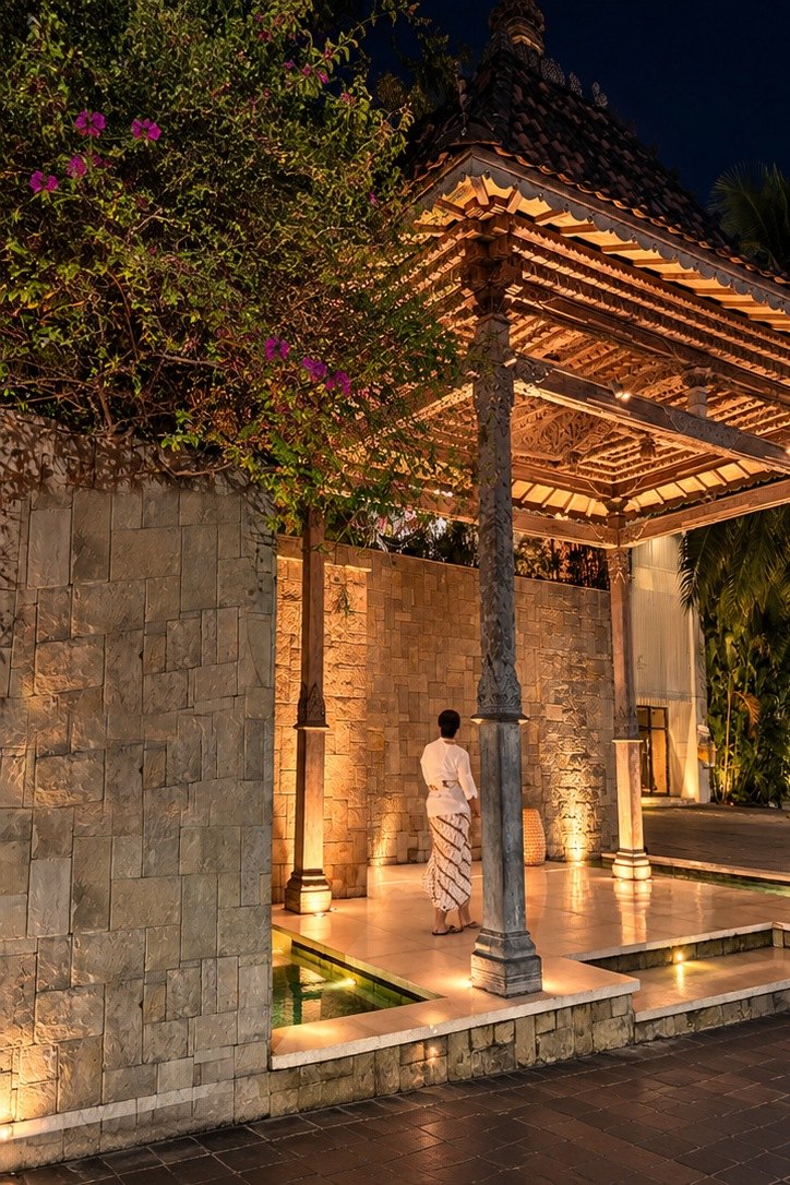 Restaurant entrance pavilion lit at night beside a stone wall