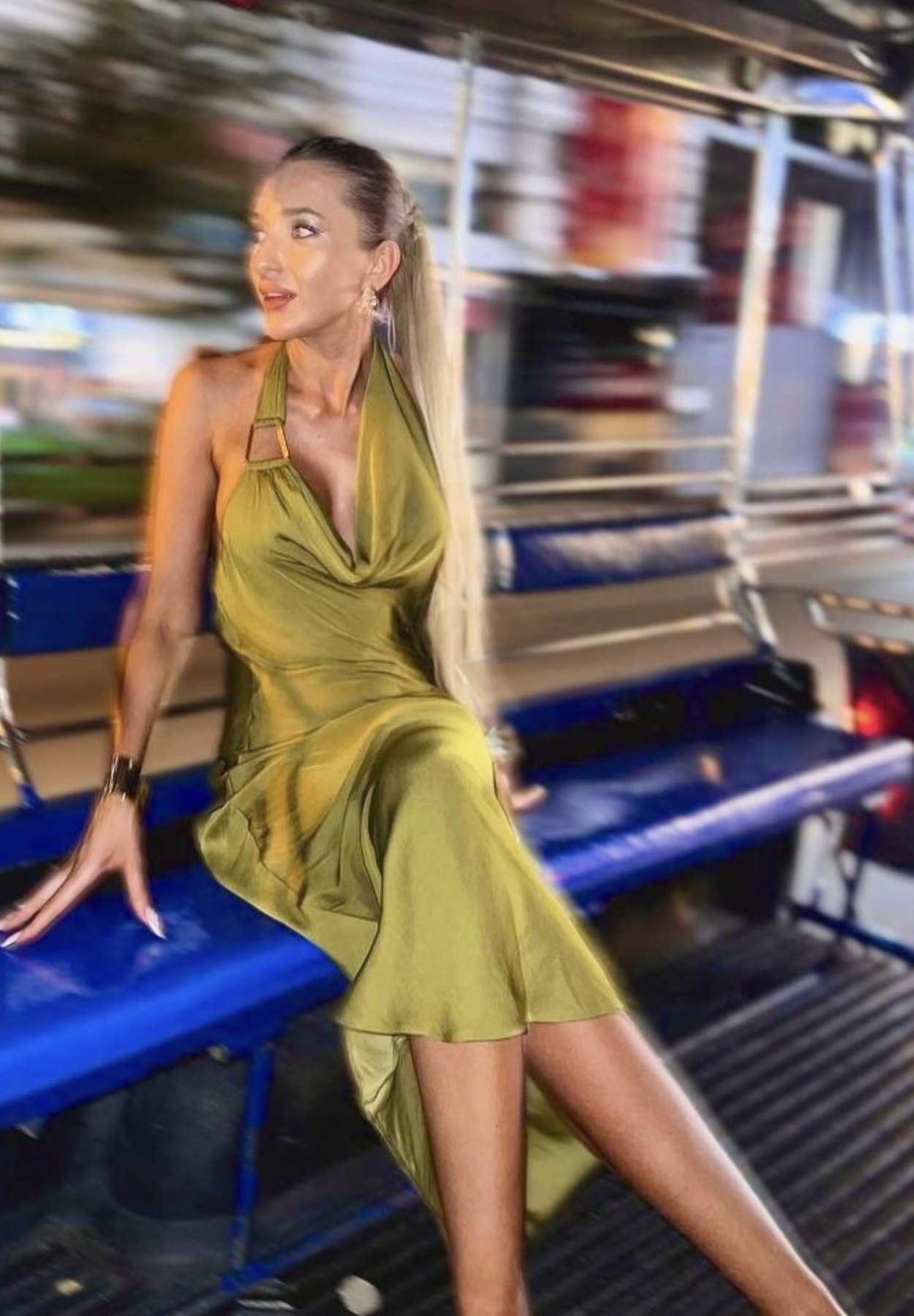 Model in an olive satin dress seated in a Bangkok songthaew at night